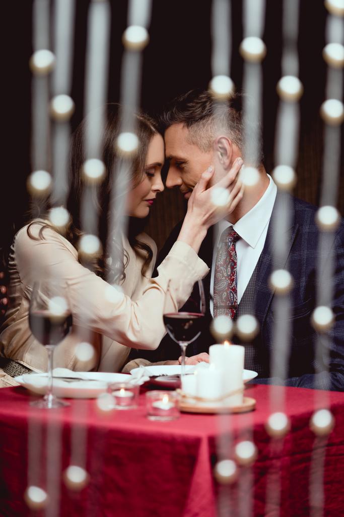 γυναίκα απαλά να αγγίζετε το πρόσωπό του ανθρώπου κατά τη διάρκεια της ρομαντική ημερομηνία στο εστιατόριο - Φωτογραφία, εικόνα
