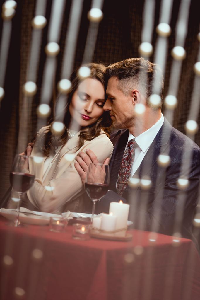 чоловік м'яко приймає жінку під час романтичного побачення в ресторані з боке світло на передньому плані
 - Фото, зображення