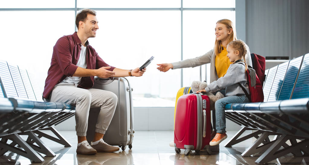 souriant père donnant des passeports avec des billets d'avion à la femme près de la fille à l'aéroport
  - Photo, image