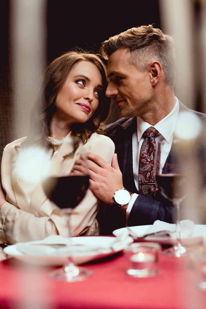 man embracing beautiful smiling woman during romantic date in restaurant - Photo, Image