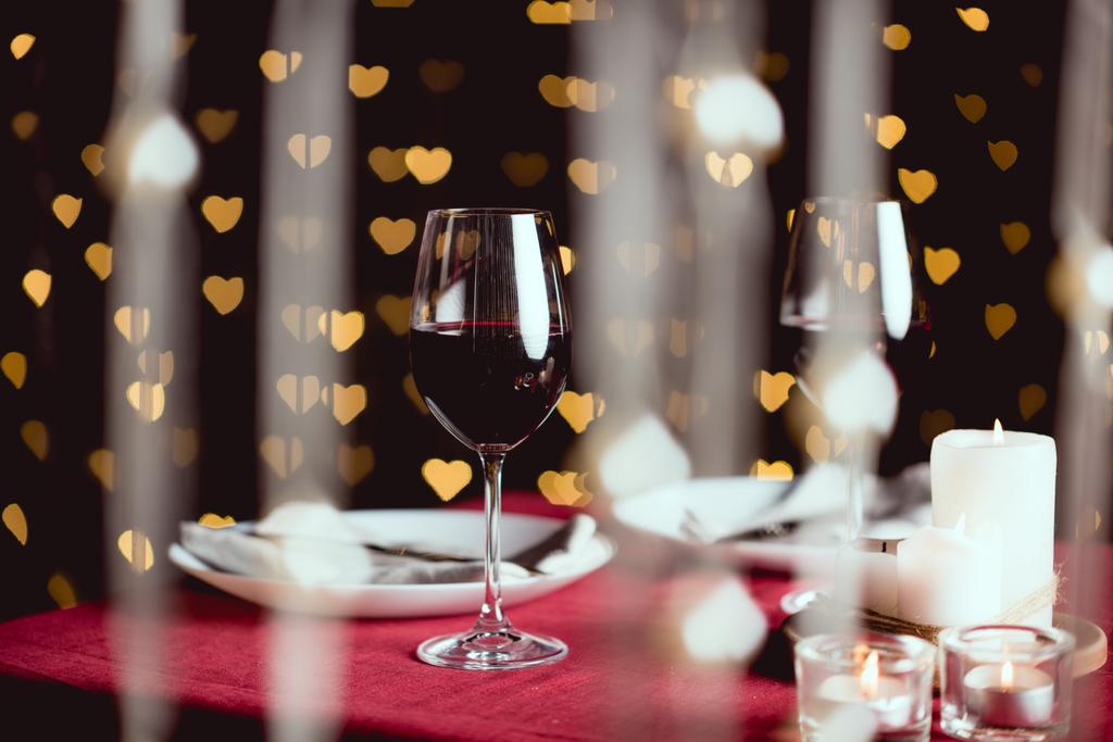 fuoco selettivo di bicchieri di vino rosso con bokeh a forma di cuore su sfondo
 - Foto, immagini