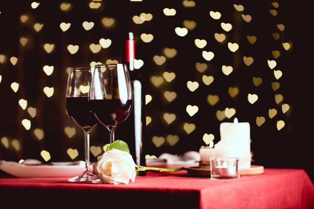 tabela ustawienia z szklanki czerwonego wina, rose i bokeh na tle w kształcie serca - Zdjęcie, obraz