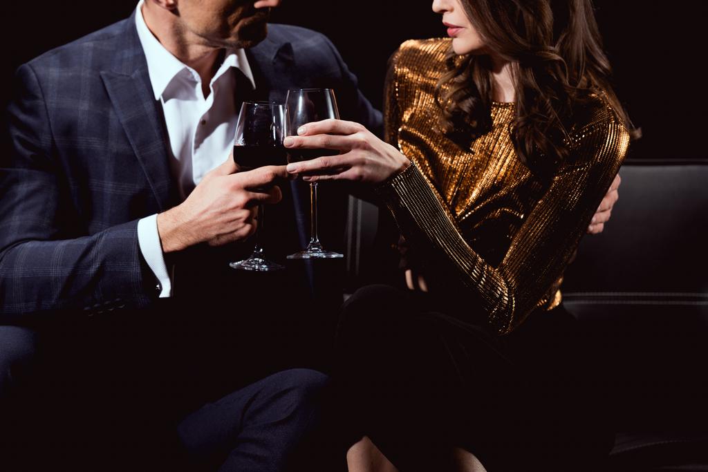 cropped view of couple clinking glasses of red wine isolated on black - Photo, Image