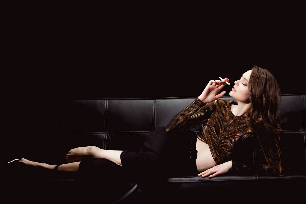 belle femme glamour couché sur le canapé et fumer cigarette isolé sur noir
 - Photo, image