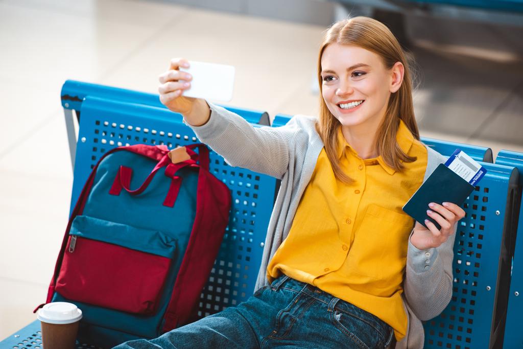 selective focus of cheerful woman taking selfie in airport  - Photo, Image