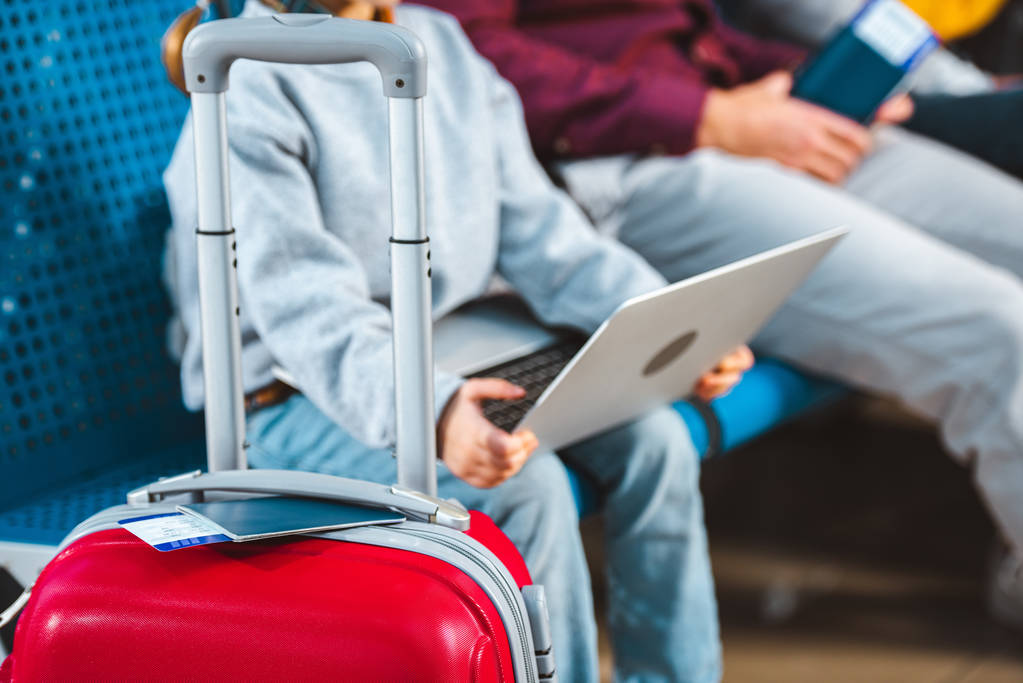 foco seletivo de bagagem com criança usando laptop em segundo plano
  - Foto, Imagem