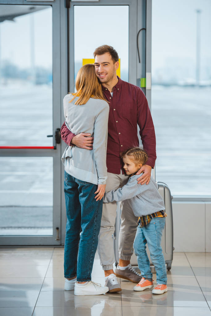 bonito homem abraçando mulher e filha no aeroporto
  - Foto, Imagem