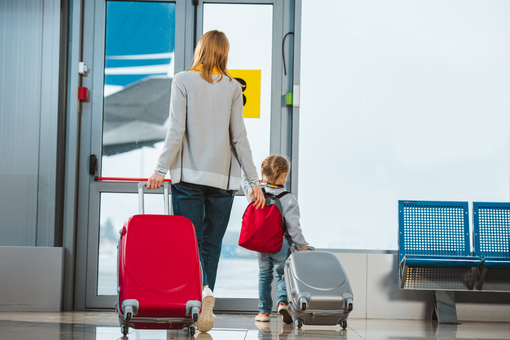 vue arrière de la mère et de la fille marchant avec des valises dans le salon de départ
 - Photo, image