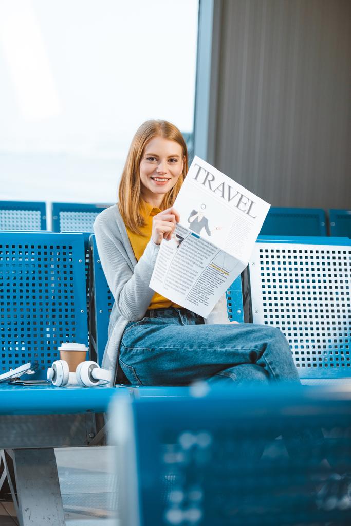çekici kadın gidiş salonunda seyahat gazetesi tutarken gülümseyen - Fotoğraf, Görsel