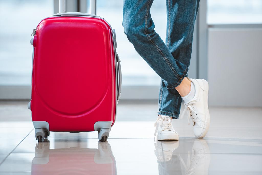 nő a bőröndöt a keresztezett lábak repülőtéren állandó levágott megtekintése  - Fotó, kép
