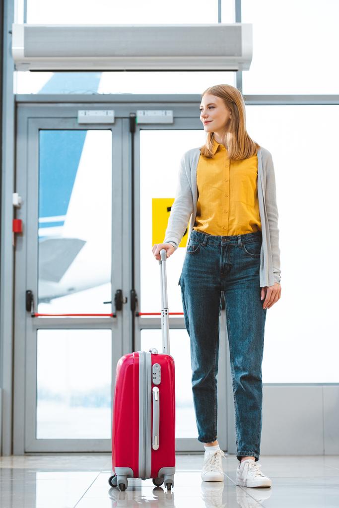 mulher atraente de pé com bagagem no aeroporto
  - Foto, Imagem