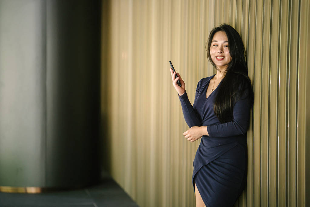 Retrato de una joven y hermosa mujer china asiática sosteniendo teléfono inteligente
 - Foto, Imagen