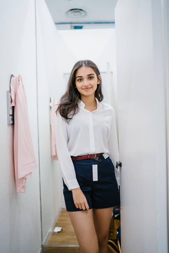 Portrait of a young, tall, beautiful and elegant Indian Asian woman trying out clothing in a fitting room at a fashion store. - Photo, Image