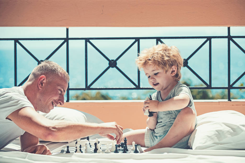 Mies opettaa pojalle shakin säännöt - leikkii parvekkeen lattialla
. - Valokuva, kuva