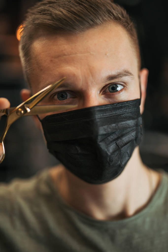 Peluquero usar máscara y mantenga las tijeras cerca de su cara. - Imagen
 - Foto, imagen