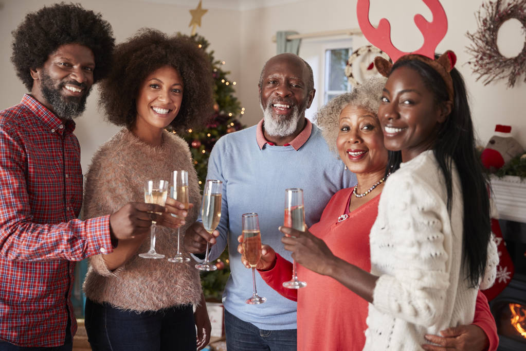 Muotokuva vanhemmista, joilla on aikuisia jälkeläisiä, jotka tekevät paahtoleipää samppanjan kanssa, kun he viettävät joulua yhdessä
 - Valokuva, kuva