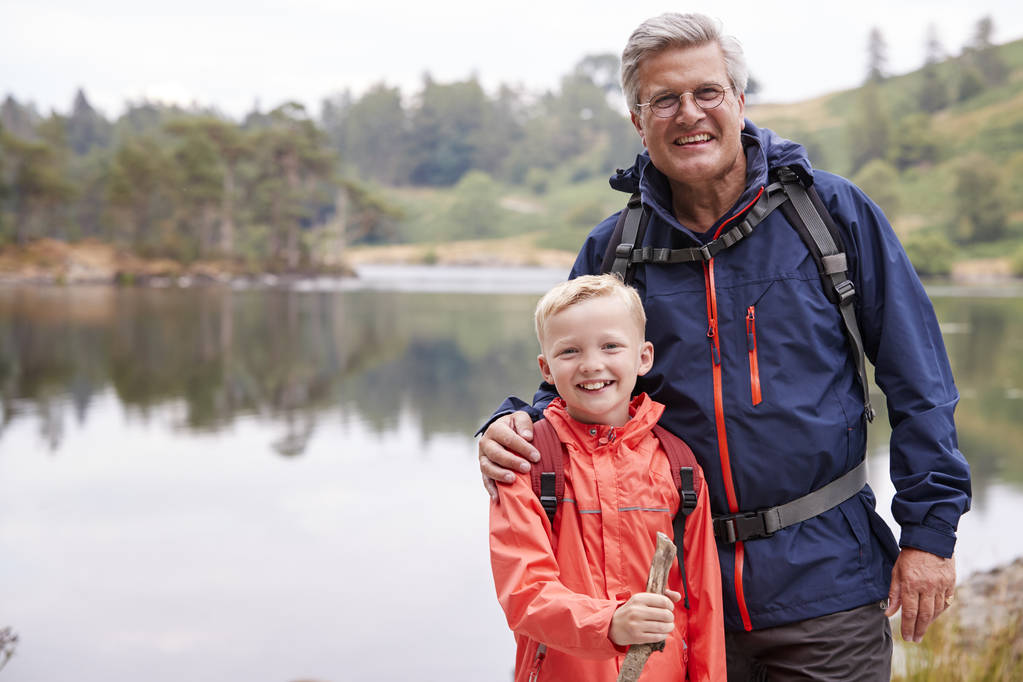 Dziadek i wnuk razem stojący na brzegu jeziora, uśmiechając się do kamery, zbliżenie, Lake District, Wielka Brytania - Zdjęcie, obraz