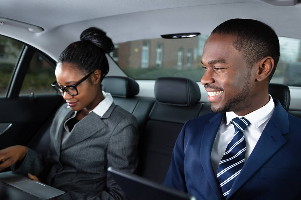 Dos empresarios africanos felices usando dispositivos electrónicos mientras viajan en coche
 - Foto, Imagen