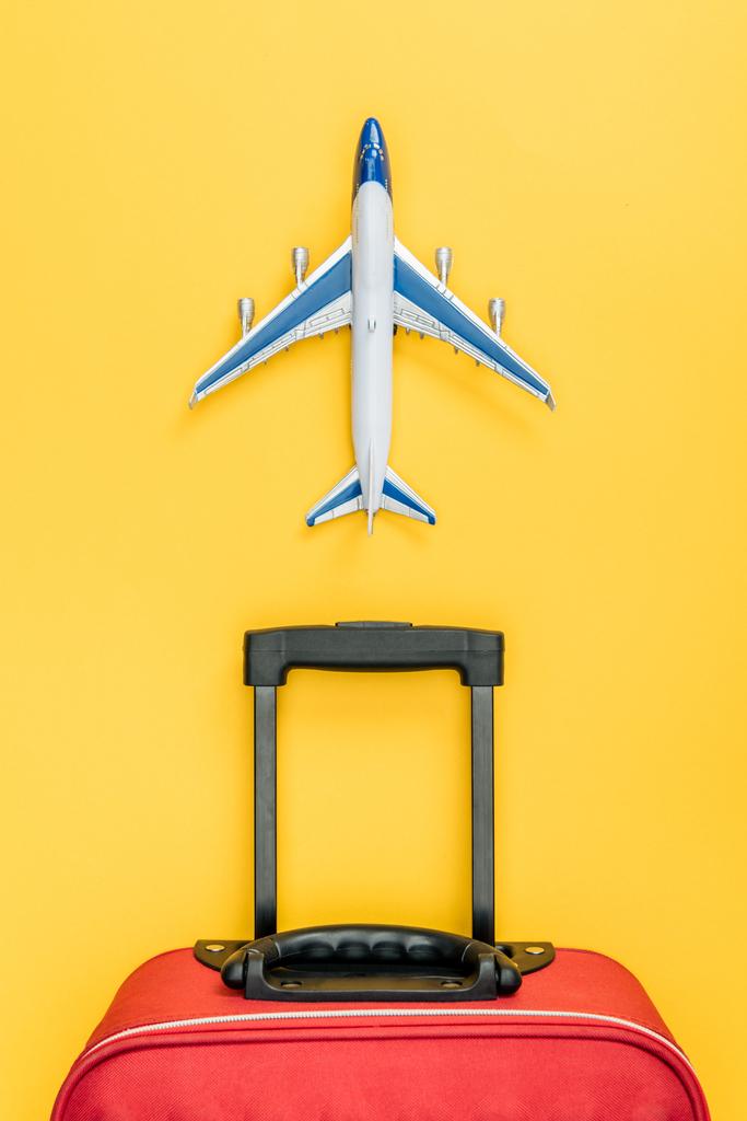 top view of red baggage and toy plane on yellow background  - Photo, Image