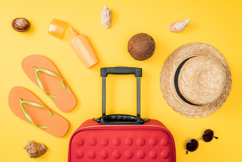 верхний вид соломенной шляпы, солнцезащитные очки, кокосовые, шлепанцы, дорожная сумка и ракушки на желтом фоне
  - Фото, изображение