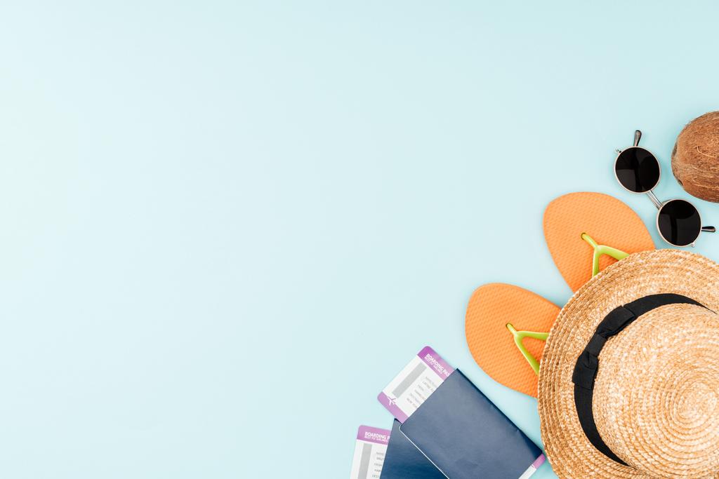 Sonnenbrille, Flip Flops, Strohhut, Kokosnuss und Reisepässe mit Flugtickets auf blauem Hintergrund  - Foto, Bild