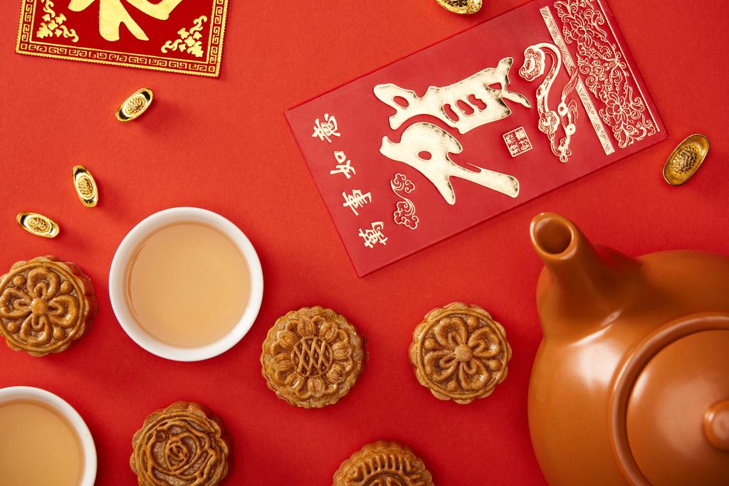 pohled shora na tradiční mooncakes s čínskými hieroglyfy a izolované na červené čaje - Fotografie, Obrázek