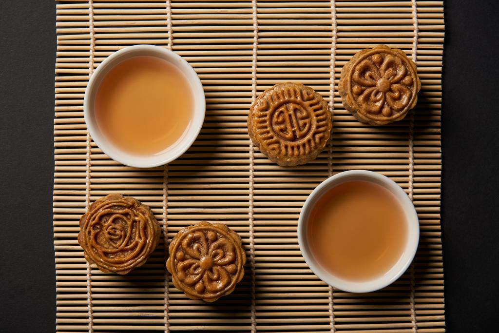 vista dall'alto delle tradizionali torte di luna e tazze da tè sul tappetino di bambù
 - Foto, immagini