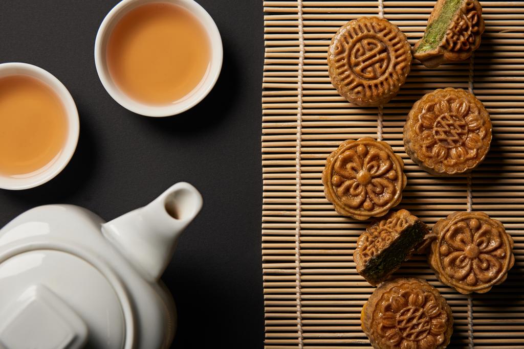 top view of traditional mooncakes, tea pot and cups on bamboo table mat - Photo, Image