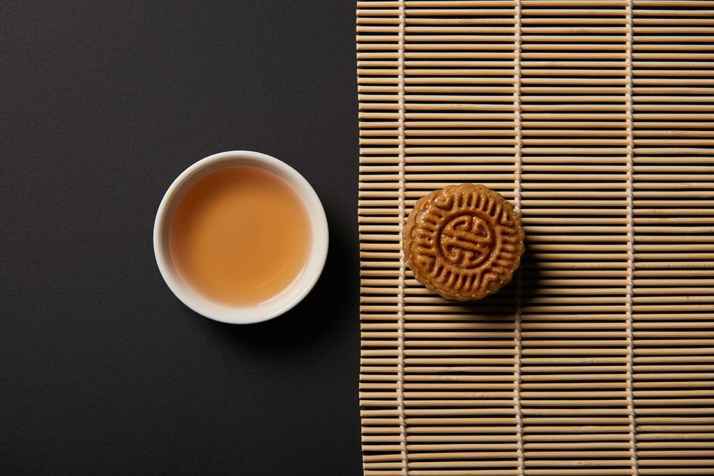 το Top view mooncake και φλιτζάνι τσάι σε χαλί μπαμπού πίνακα - Φωτογραφία, εικόνα