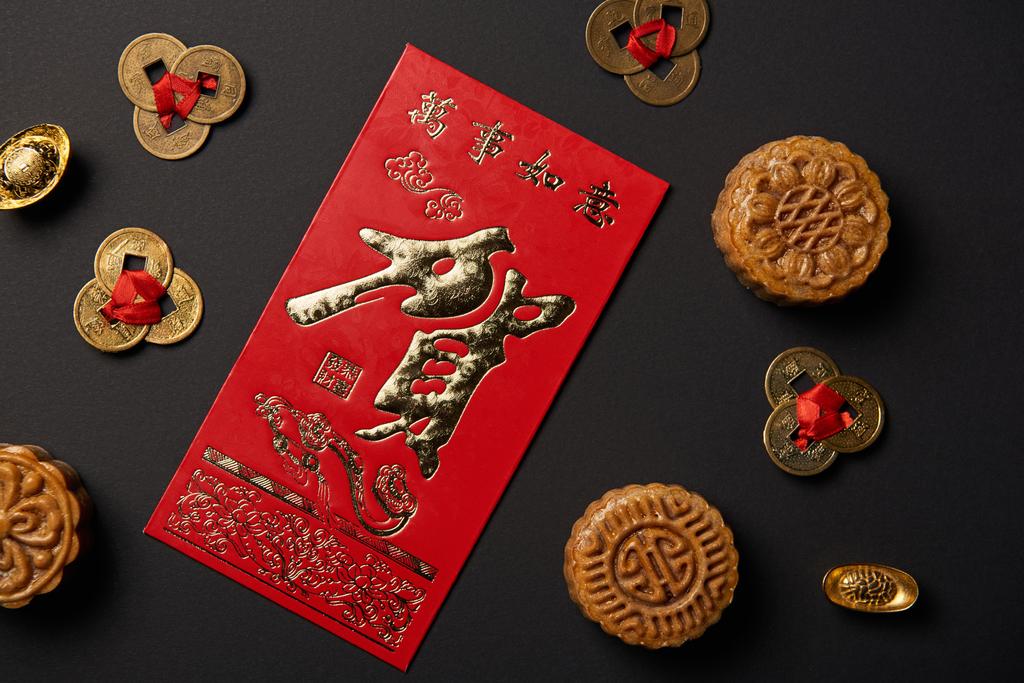 κάτοψη του παραδοσιακού mooncakes με κινέζικα ιερογλυφικά και feng shui νομίσματα απομονώνονται σε μαύρο - Φωτογραφία, εικόνα