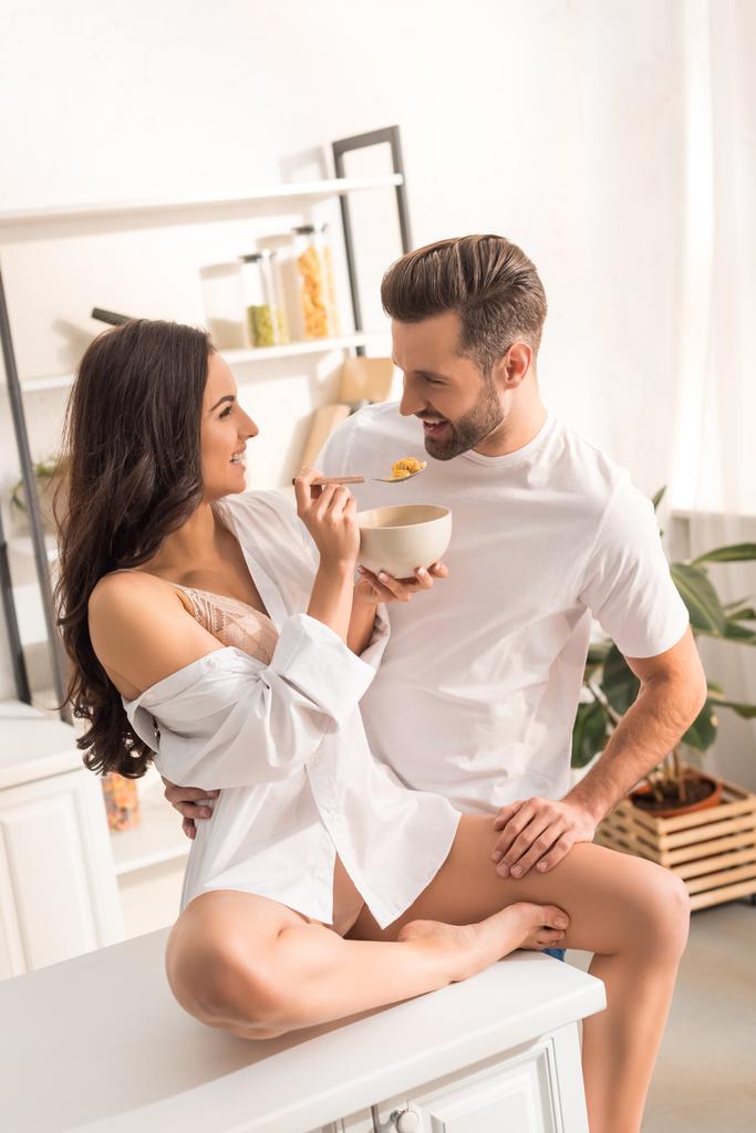 усміхнена жінка годує чоловіка зерном під час сніданку вранці
 - Фото, зображення