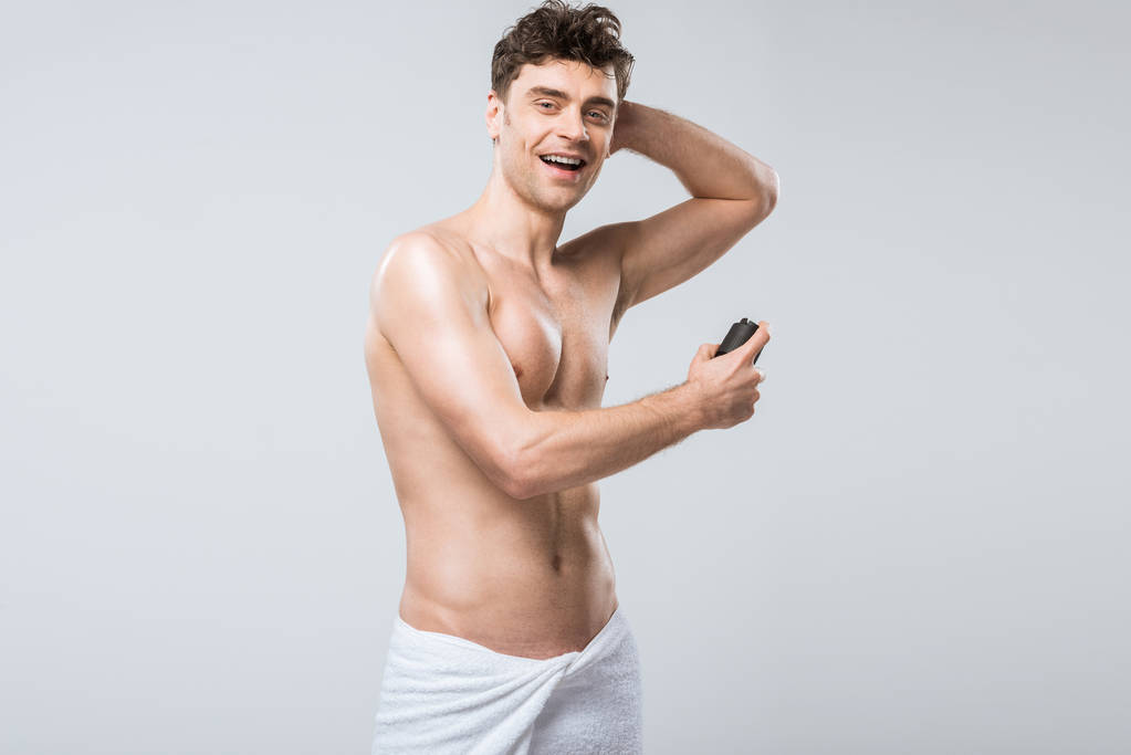 красивый без рубашки возбужденный мужчина, распыляющий дезодорант, изолированный на сером
 - Фото, изображение