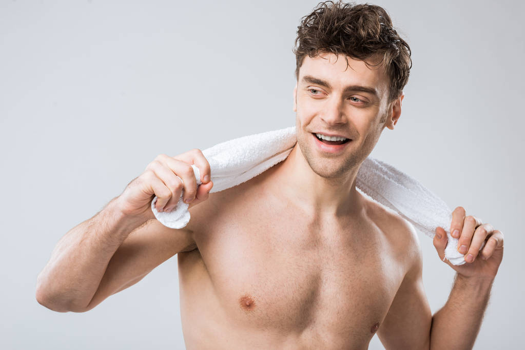 красивый улыбающийся мужчина, держащий белое полотенце, изолированное на сером
 - Фото, изображение