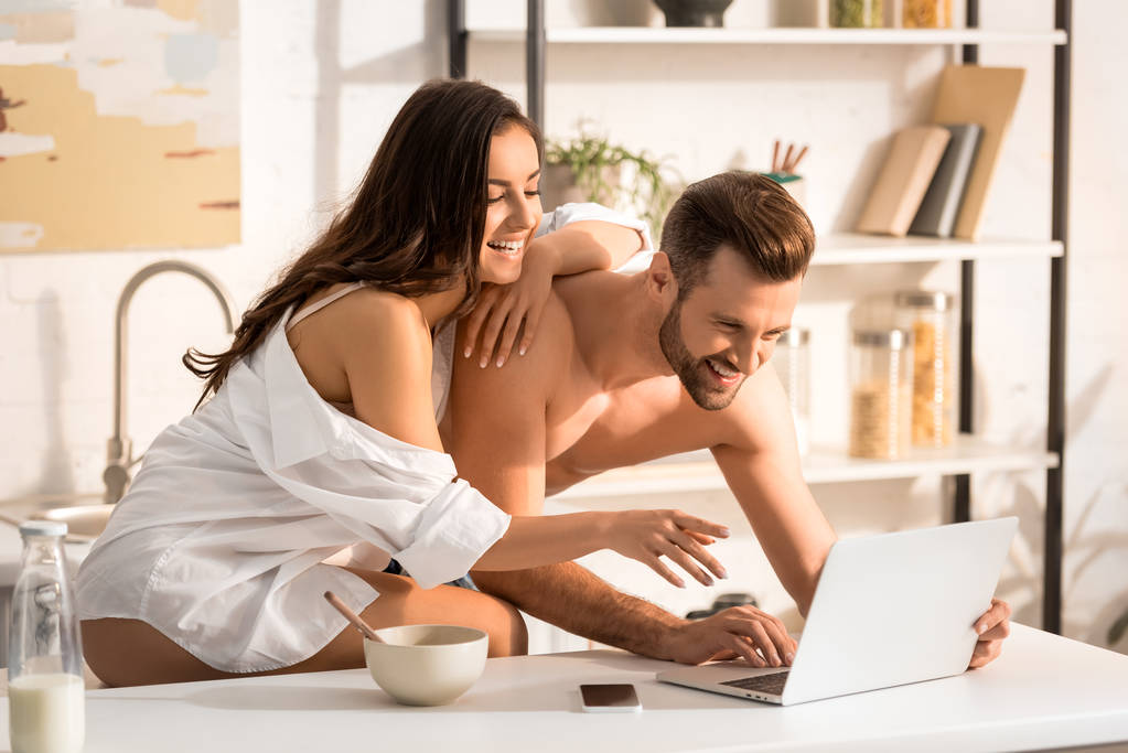 όμορφη σέξι ζευγάρι χρησιμοποιώντας φορητό υπολογιστή κατά τη διάρκεια του πρωινού στο σπίτι - Φωτογραφία, εικόνα