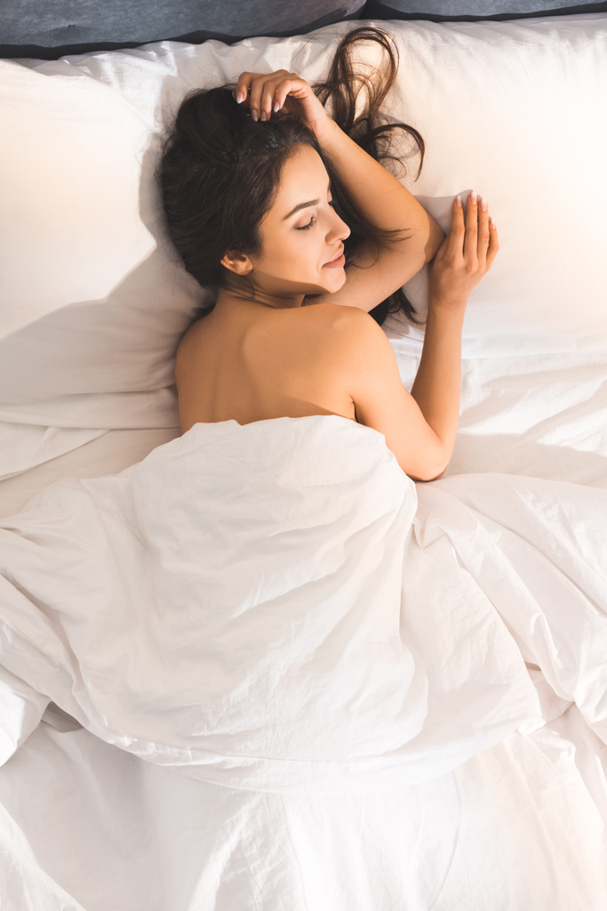 Top view of beautiful nude woman sleeping in bed at home in morning
 - Фото, изображение