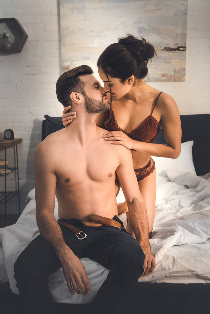 mujer seductora en lencería abrazando al hombre sin camisa en la cama
 - Foto, imagen