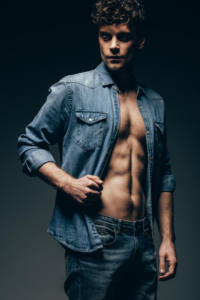 красивый сексуальный мужчина позирует в джинсовой рубашке изолированный на сером
 - Фото, изображение