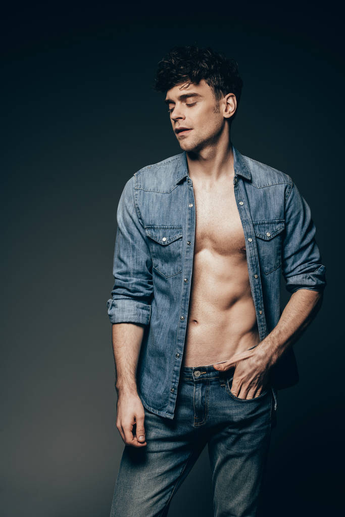 handsome sexy man posing in jeans clothes isolated on dark grey - Photo, Image