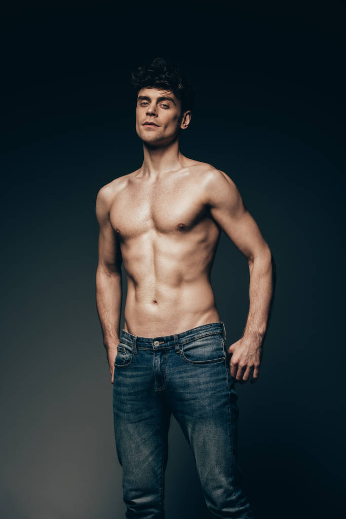 sexy macho in jeans posing isolated on dark grey - 写真・画像