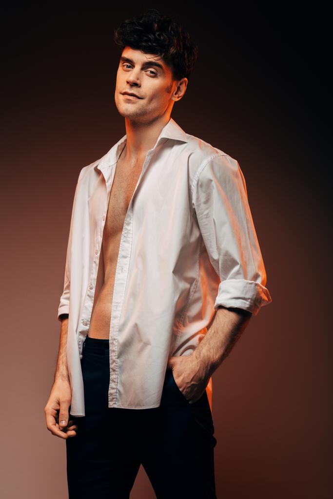 sexy elegante hombre posando en camisa blanca, aislado en marrón
 - Foto, Imagen