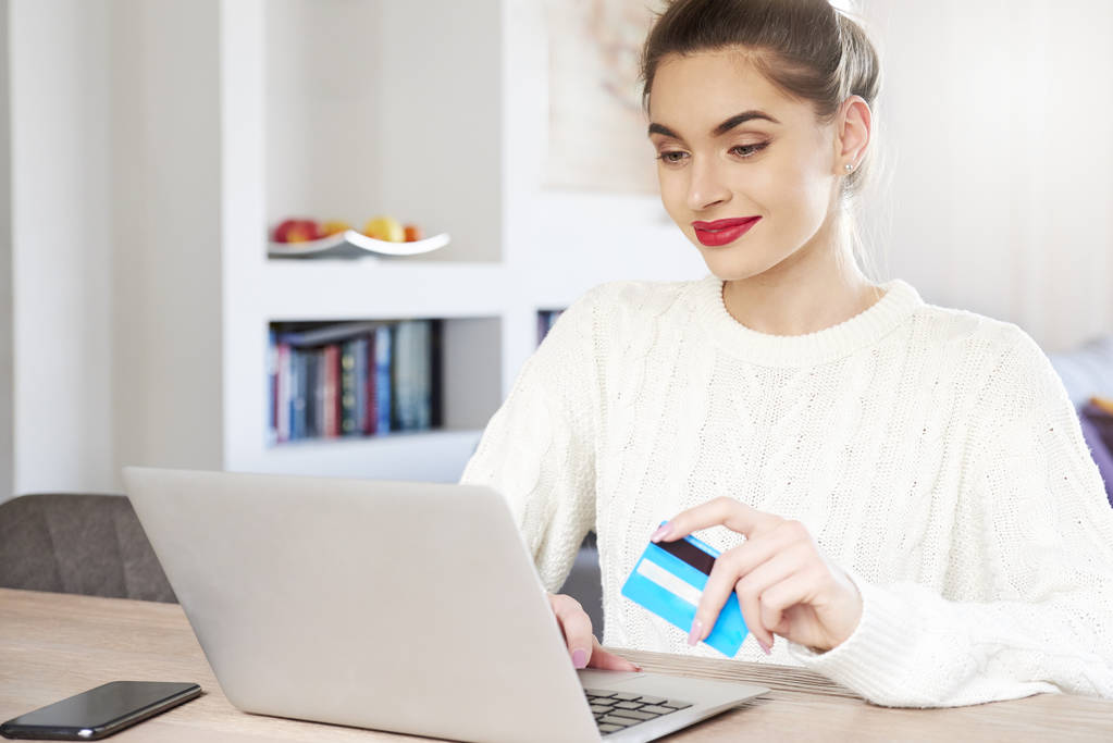 Colpo di donna che tiene la carta di credito in mano e utilizza il computer portatile durante lo shopping online a casa
.  - Foto, immagini