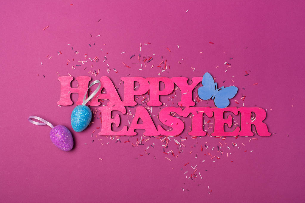 Vue du dessus sur le texte rose de Pâques heureux et des œufs scintillants avec des paillettes de sucre colorées vives ou des confettis comme décor de cuisson sur fond violet
 - Photo, image