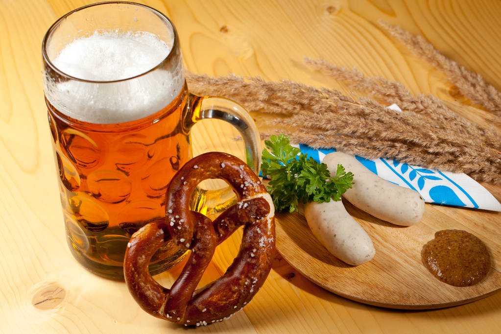 Mug of beer, pretzel and sausages on wooden table - Photo, Image