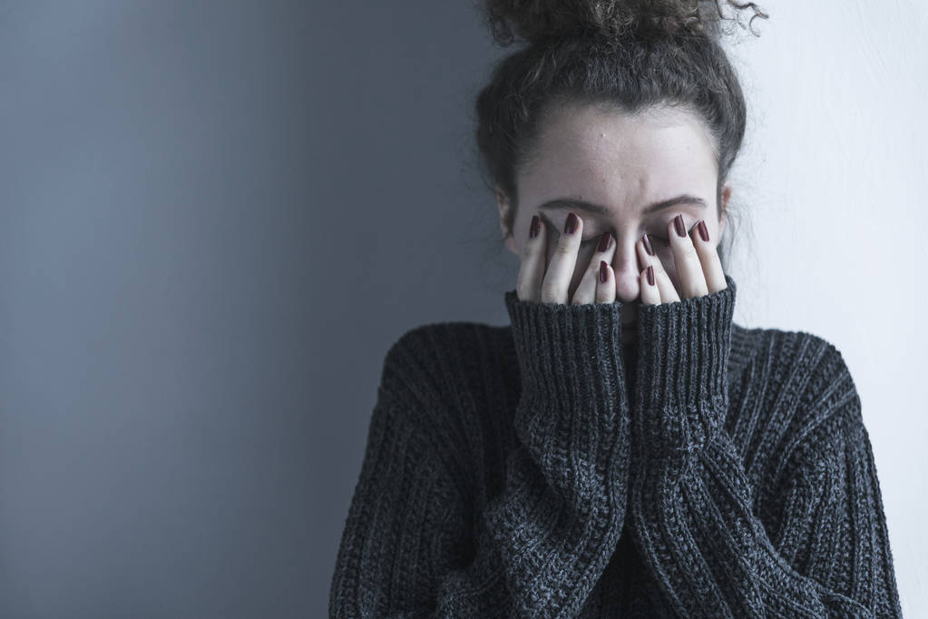 Porträt einer gestressten jungen lockigen Frau auf dunklem Hintergrund - Foto, Bild