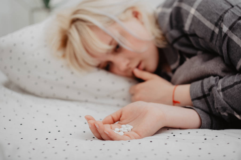 落ち込んで若い女性のベッドで横になっていると薬の palmful を保持しています。 - 写真・画像