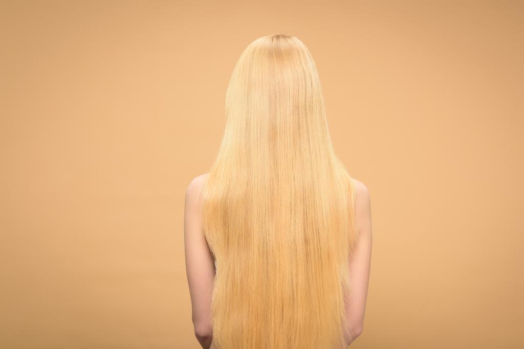Widok z tyłu długi włosy blond kobieta stojąc na beżowym tle - Zdjęcie, obraz