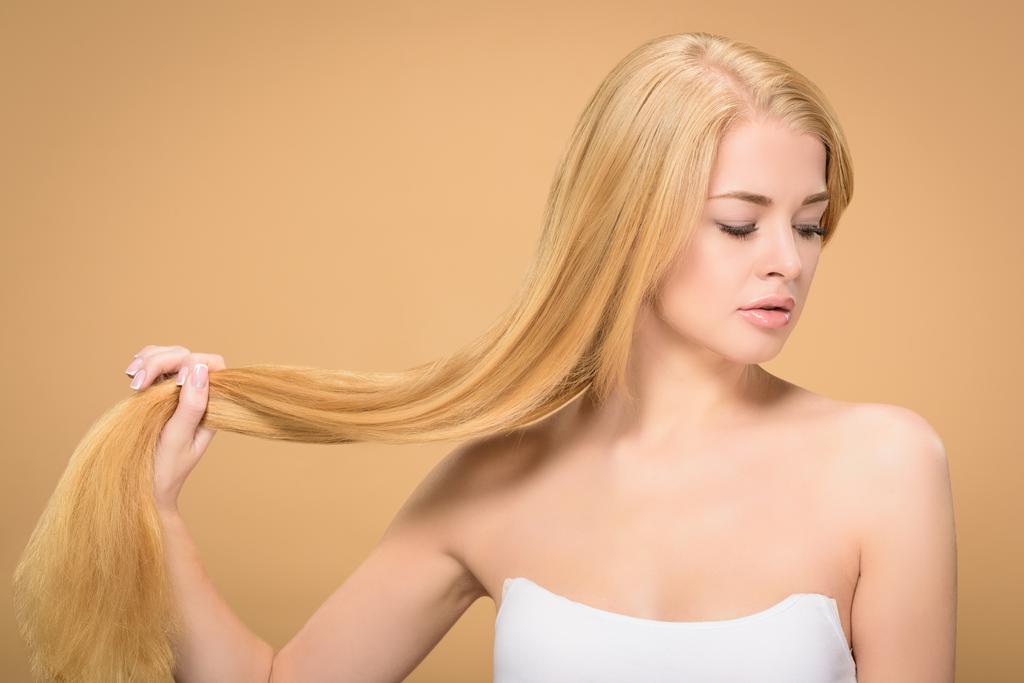 Houkutteleva nuori nainen, jolla on vaaleat hiukset kädessä
  - Valokuva, kuva