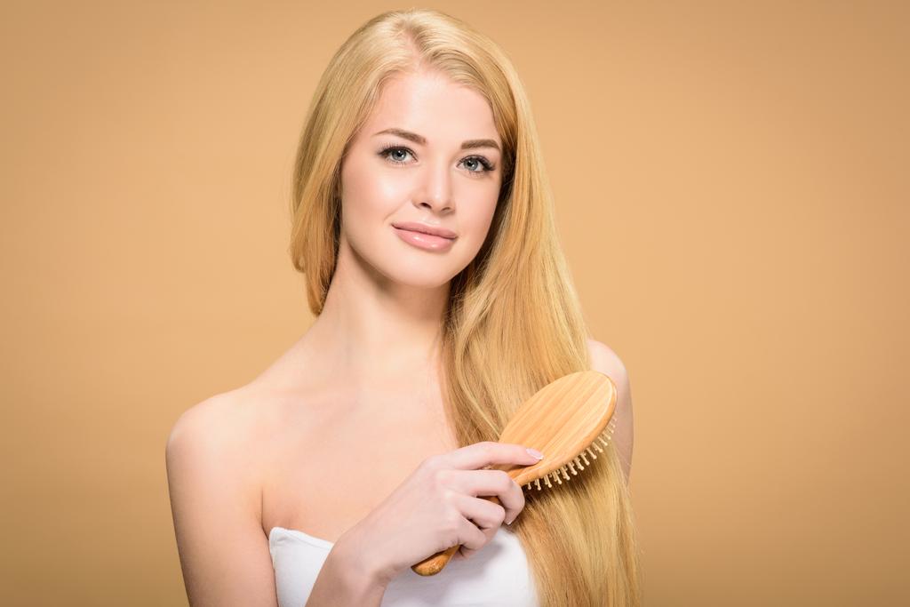 Jovem mulher escovando cabelos longos e sorrindo para a câmera
 - Foto, Imagem