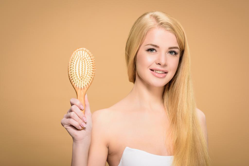 Charming girl holding wooden hair brush with sincere smile - Photo, Image