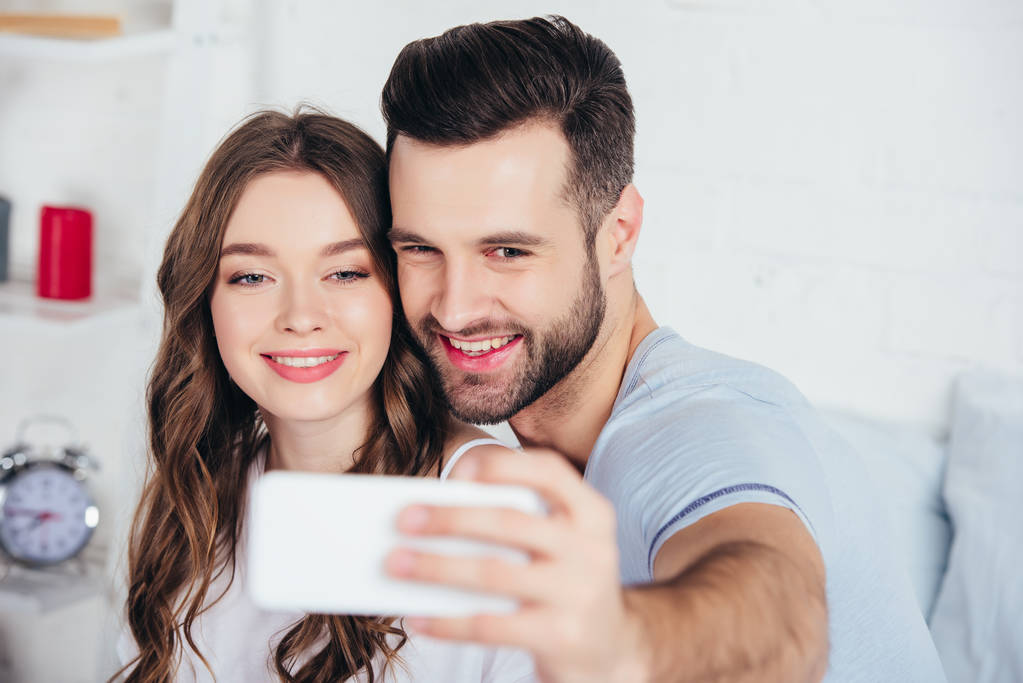 enfoque selectivo de pareja adulta sonriendo y tomando selfie
 - Foto, imagen